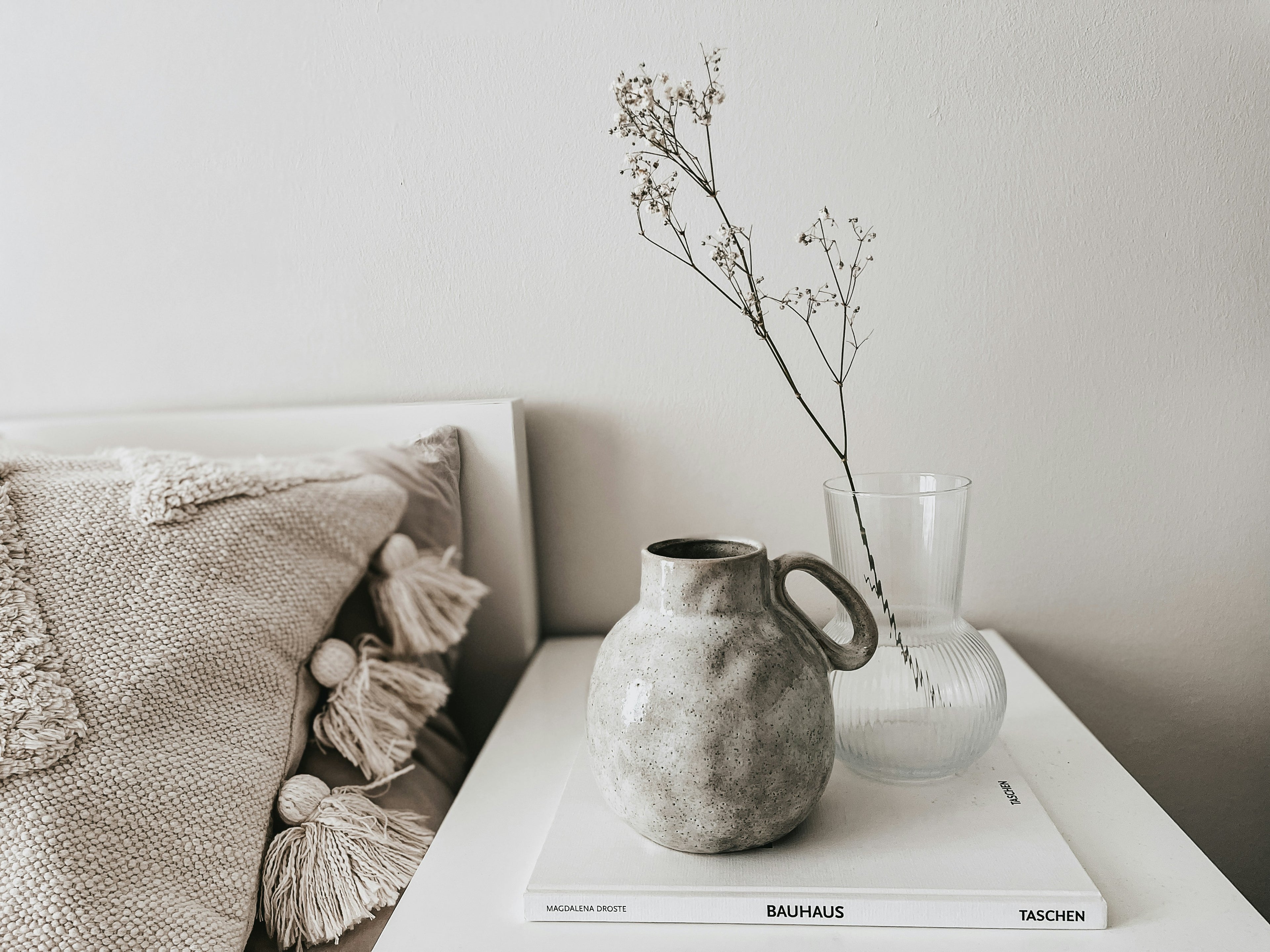 Decorative vases and a book on a white surface with a neutral background